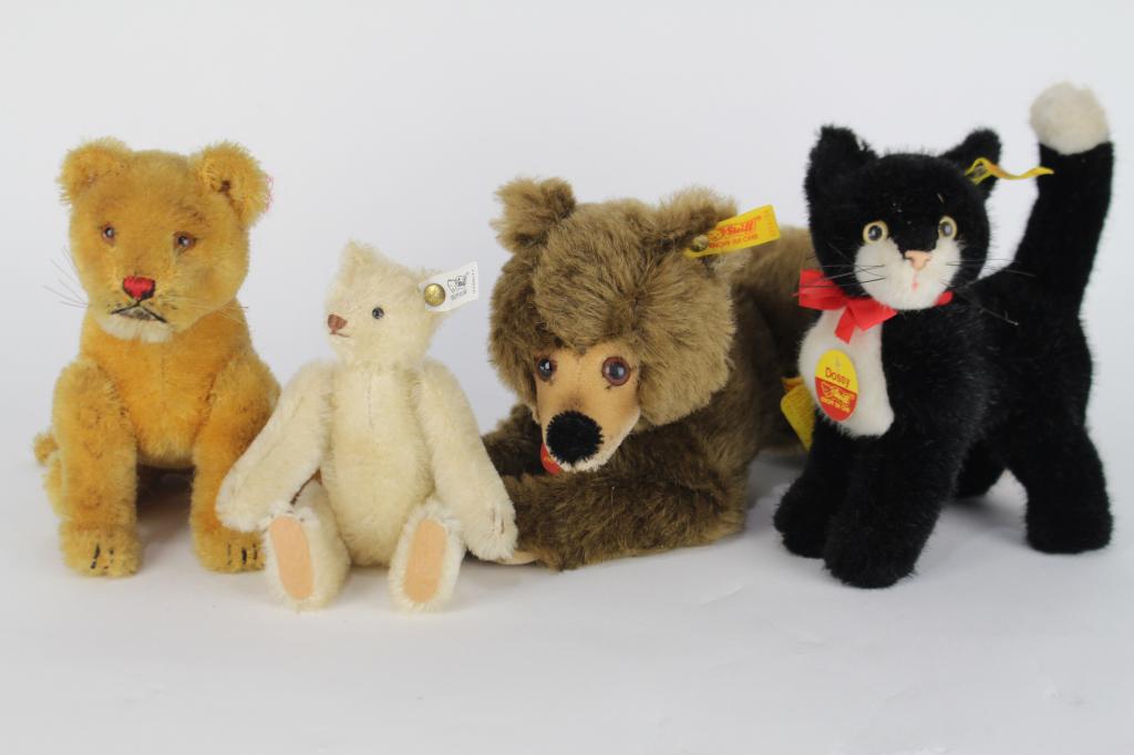 Four Steiff Stuffed Animals: 6.5" x 13" mohair bear with ear button, label and factory tag. "Dossy" black and white cat with label, button, 2 paper tags, small white mohair jointed bear with label and button and jointed mohair li