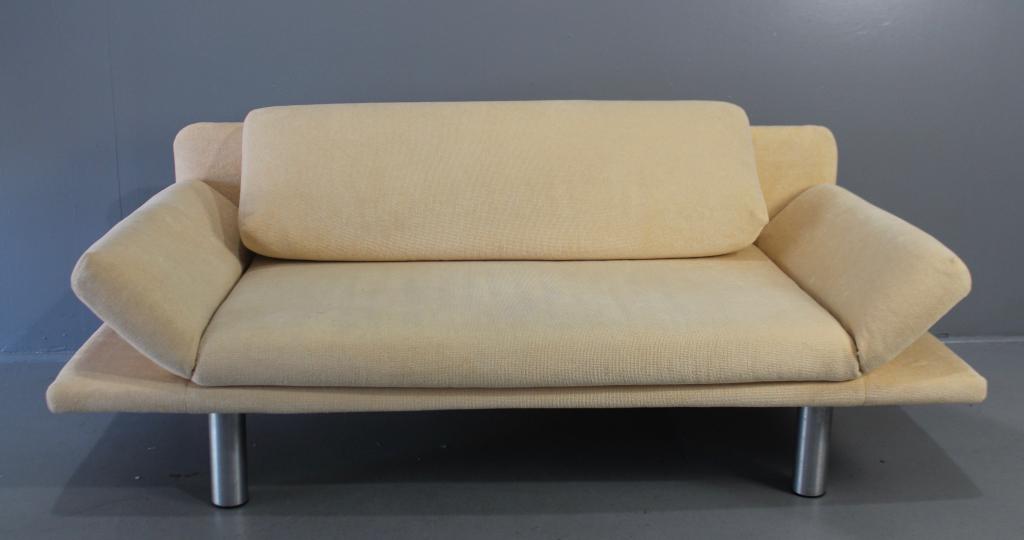 Roche Bobois Adjustable Arm Sofa: single bolster cushion back, arms adjust to day bed feature, brushed aluminum tubular front legs, upholstered in cream color fabric, 77" long x 29" tall x 33" deep, clean, good condition.