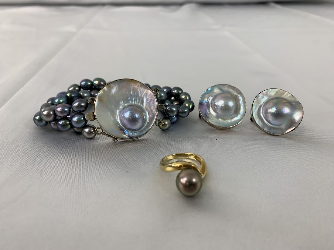 14K Gold and Black Pearl Jewelry Set: 14K Gold and Black Pearl Jewelry Set. Bracelet measures 8" with three stands of 7 mm pearls. Pair of earrings. and gold ring with a 10.25mm pearl and a tiny diamond. Ring is size 6. Good condition.