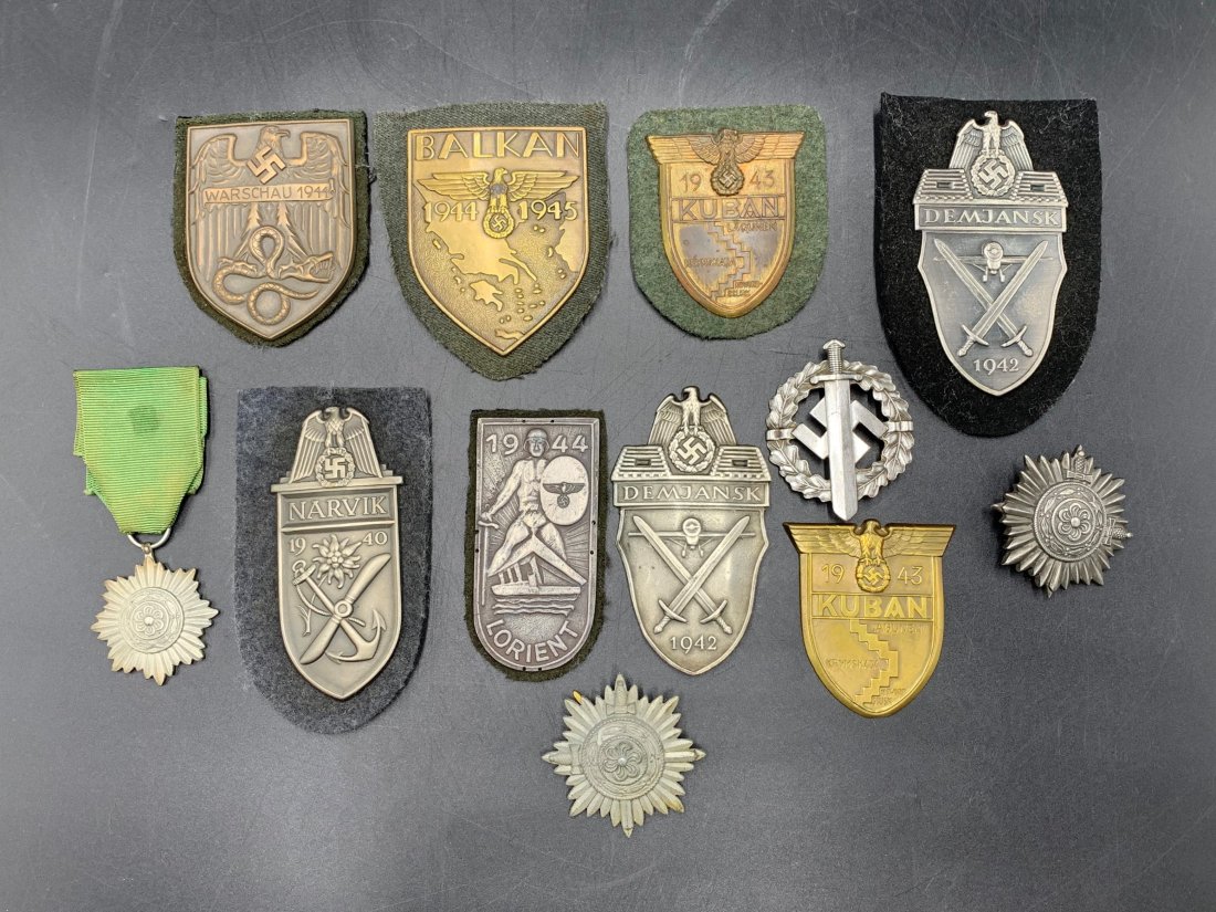 Lot of 12 German Medal & Uniform Shield Badges: Lot of 12 German Medal & Uniform Shield Badges. (1) Warschau 1944, (1) Balkan 1944, (1) Narvik 1940, (2) Demjansk 1942, (2) Kuban 1943, (1) Lorient 1944 & 5 medals. Approximately 3" to 1 1/2" in sizes