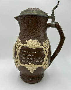 Villeroy and Boch Mettlach Lidded German Beer Stein #1028: Villeroy and Boch Mettlach Lidded German Beer Stein #1028. The stein is a tree trunk form with pewter mounted harvest design lid. It features worded mottos in German in fruited frames and a cameo reli