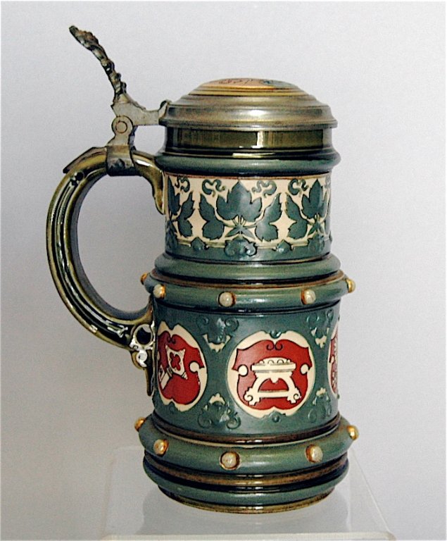 Mettlach Stein # 2012: Mettlach stein # 2012, .5L, armorial crests and green leaf design surrounding body, Viking ship lid, good condition.