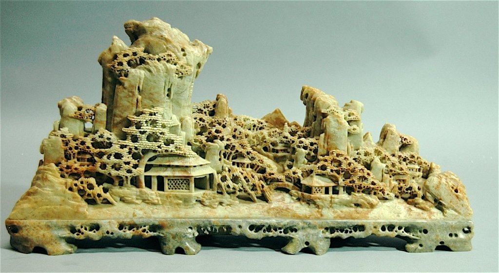 Soapstone Carving of Village: Monumental soapstone carving of small village on rocky mountain top on carved soapstone stand, 19w, 9.5h.