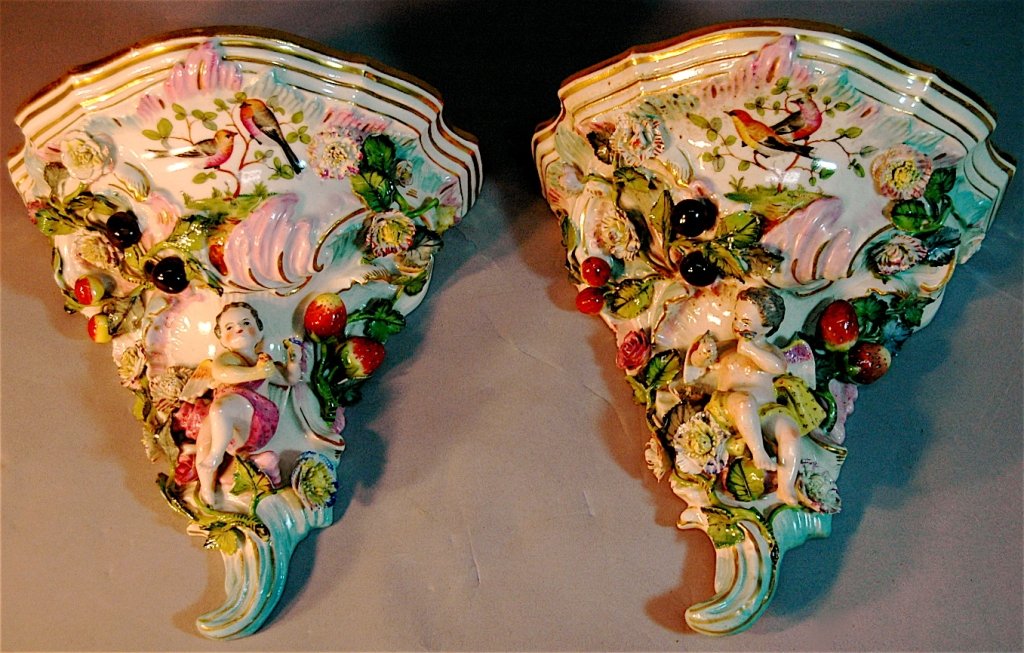 Pair of Dresdan Porcelain Sconces: Pair of Dresden porcelain wall sconces, each has winged cherub holding flowers in remarkably good condition to all parts of floral and applied fruits, under glaze mark (undetermined), label from early