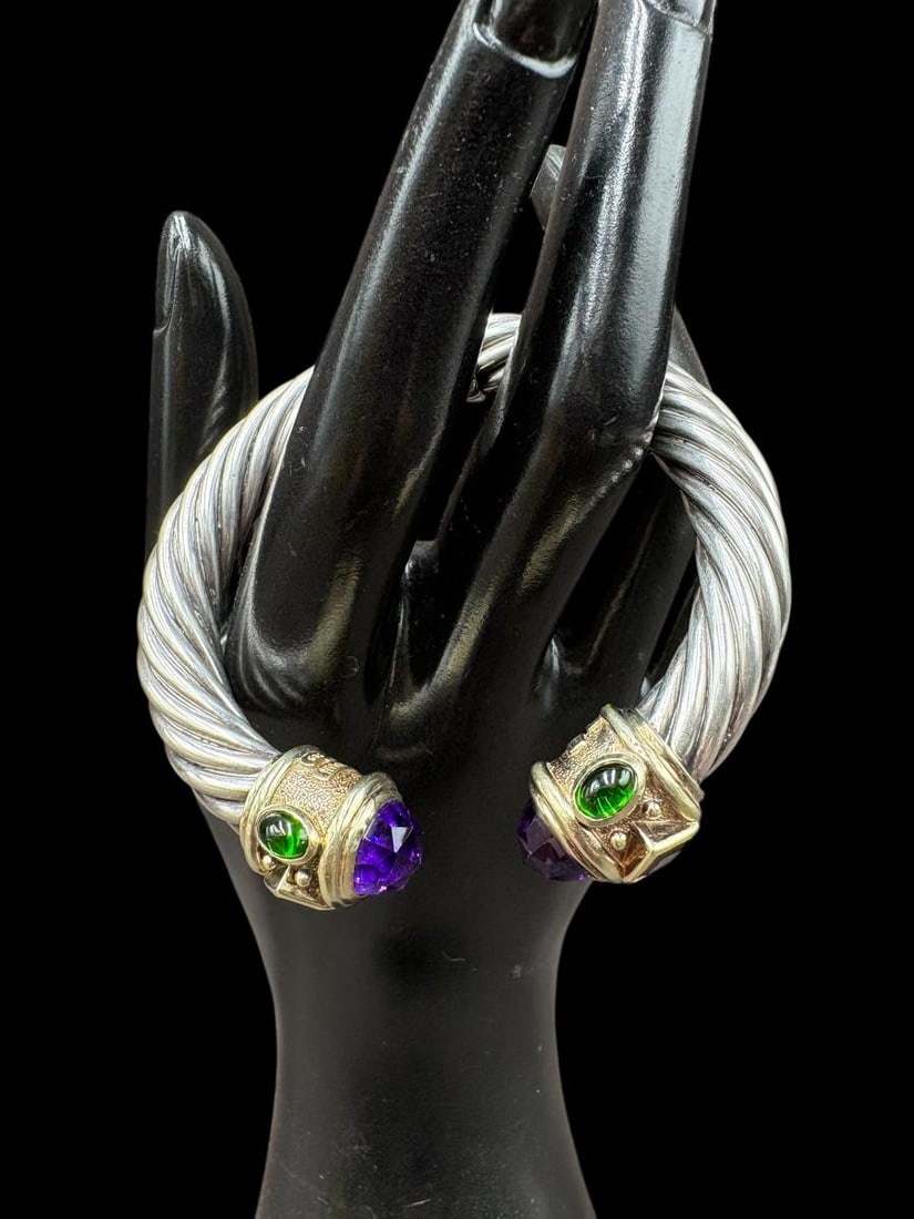 David Yurman 10mm Sterling & 14k Gold & Amethyst Cuff Bracelet Renaissance Collection: David Yurman 10mm Sterling & 14k Gold & Amethyst Cuff Bracelet Renaissance Collection. The bracelet has amethyst stones on the ends flanked by a band of 14k gold with emerald and garnet stones. The br