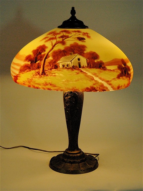Scenic Reverse Painted Table Lamp: Scenic reverse painted table lamp, attributed to Jefferson. 2 bulb socket, shade is numbered 730. Base is numbered 1942. Shade has minor factory interior rim chip. Gold painted white metal base, cast 