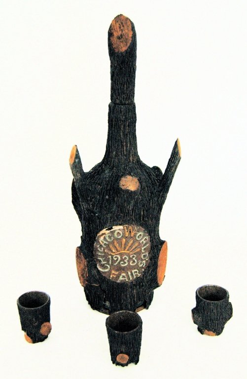 1933 Chicago World's Fair Decanter Set: Unusual Chicago World's Fair decanter set, with decanter, stopper and 3 shot glasses. This set is glass covered with tree bark. The medallion is colored gesso. There are missing places on the covering