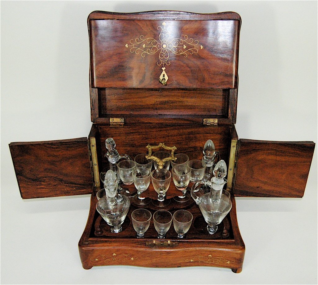 Brass Inlaid Tantalus: Brass inlaid Tantalus with lock and key, has full fitted interior with all components. 16 glasses, 4 decanters with stoppers. Top opens the sides swing-out. Decanters and glasses lift out with holder.