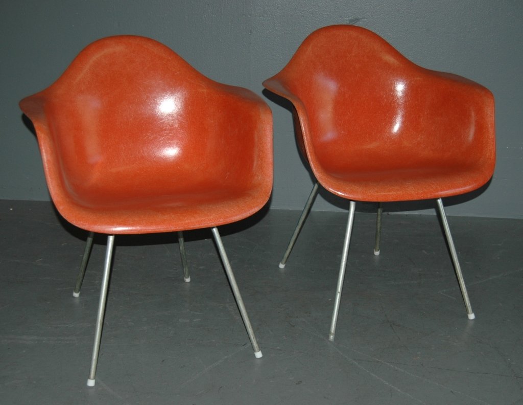Two Herman Miller Molded Shell Chairs: Two Herman Miller molded fiberglass arm chairs in orange. Designed by Charles and Ray Eames, c. 1955. All original with paper label and raised Miller mark. Very good condition.