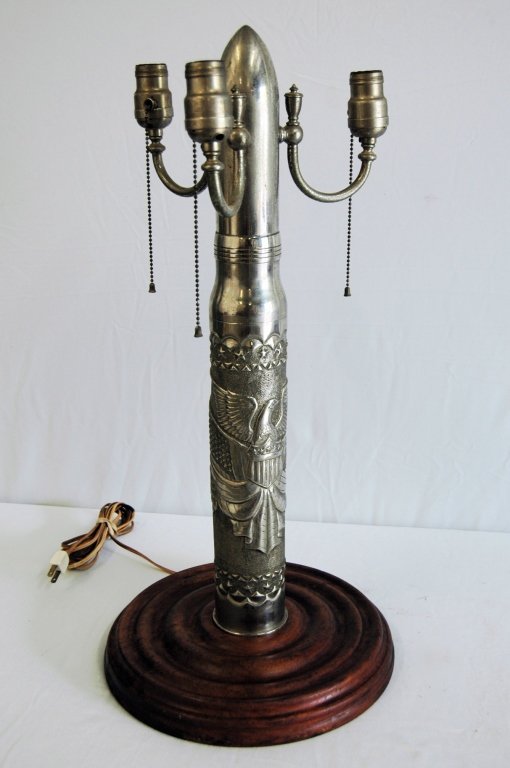 Trench Art Shell Table Lamp: Trench Art table lamp with 3 socket light fixture, nickel plated brass cannon shell with American Eagle shield art work. Fitted on 12.5" turned walnut base. Consignor states his father made this piece