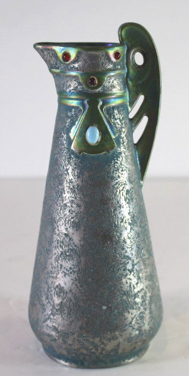 Amphora Porcelain Ewer: Amphora iridescent porcelain ewer, deep green textured glaze, applied cabochon jewels, shape number and signature obscured by glaze, 11" and good condition.