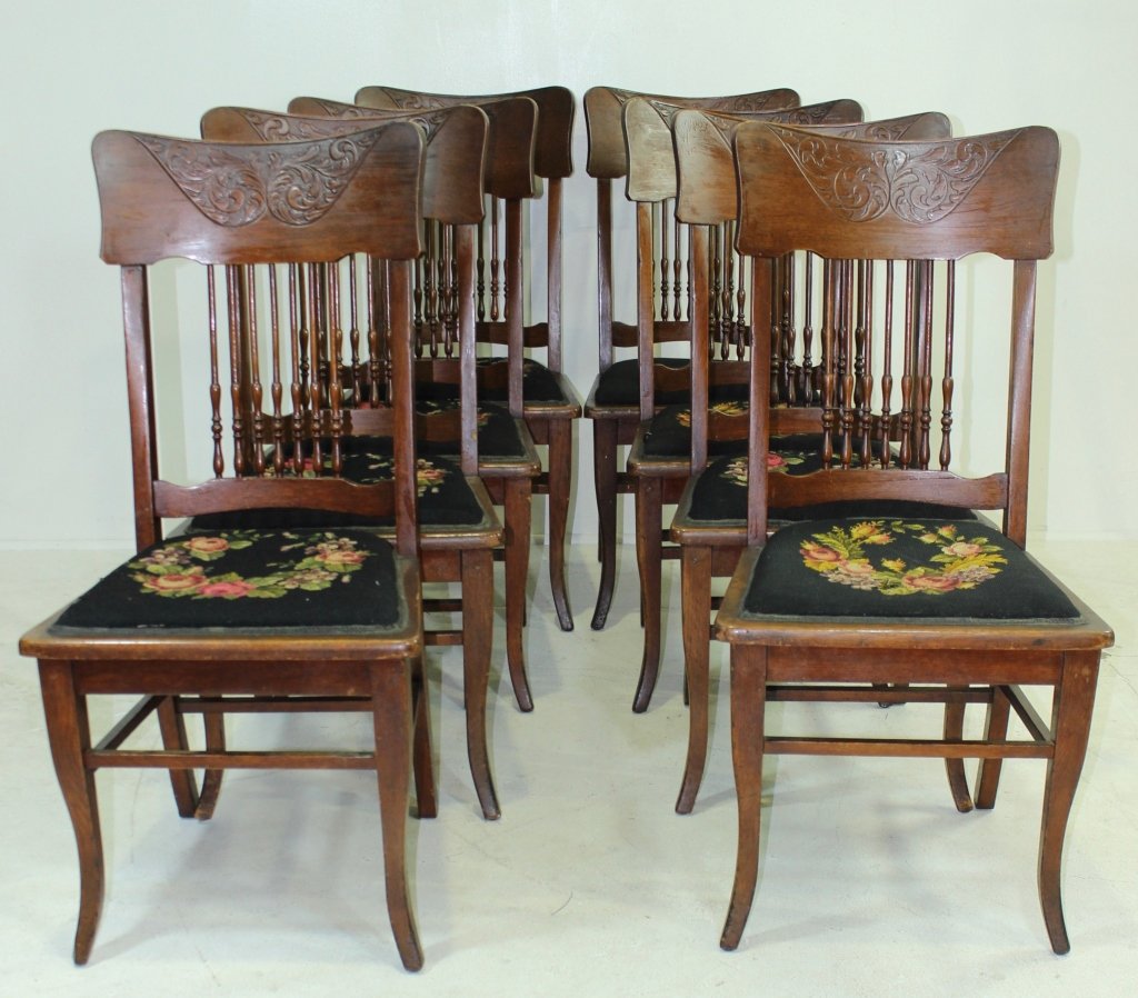 Eight Oak Pressed Back Dining Chairs: Eight oak pressed back dining chairs, spindle backs stretchers all around legs, 7 with floral wreath needlepoint seats, c. 1910. 41"h, 18"w, 18"d.