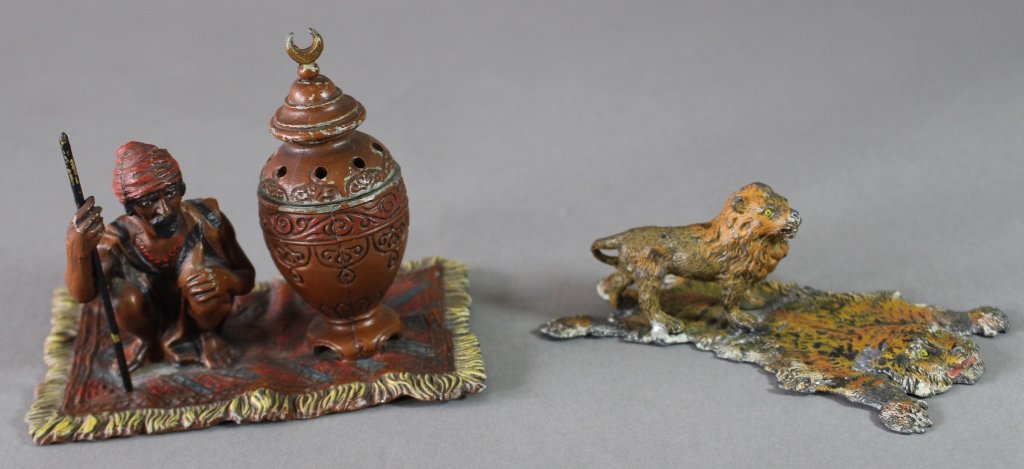 Two Austrian Cold Painted Figurines: Two Austrian cold painted spelter figurines: Lion figure standing on tiger skin rug 5" x 3" and man with staff squatting on Oriental carpet next to urn (incense burner), 5" x 3.5" x 4" tall. Both in g