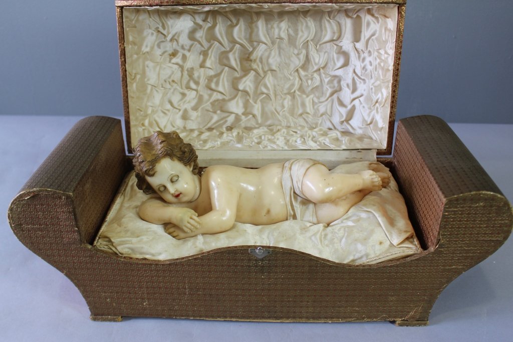 Automaton Wax Baby Doll in Box: Automaton wax baby doll on satin couch in hinged box. Music box plays and head moves (slightly), sleep eyes open with head movement, right arm needs reattachment, as a whole unit needs adjustment, box