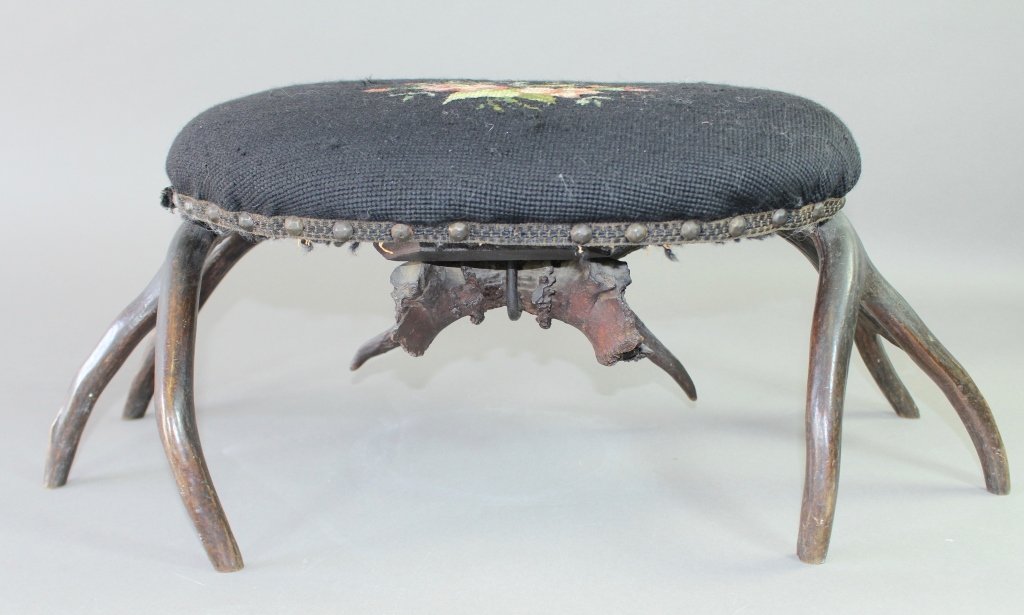 Needlepoint Footstool with Stag Legs: Needlepoint footstool with stag legs. Expertly assembled with antlers notched and crossed for strength, seat 17" x 12", height 10", 24" x 12" leg spread. Fine condition.