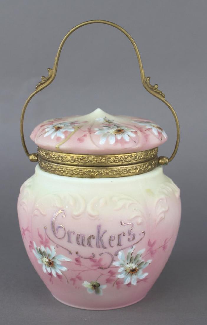 Nakara by C. F. Monroe Co. Cracker Jar: Nakara by C.F. Monroe Co. cracker jar, fine example with enameled floras, silver lettering, pinkish tint to body, excellent condition, signed, 7"h, 6" diameter.