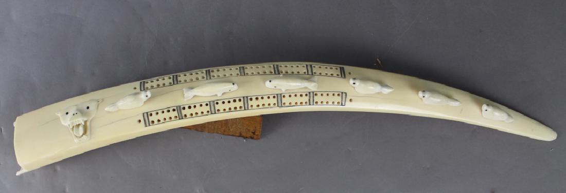 Inuit Folk Art Carved Walrus Tusk: Fine Inuit folk art carved walrus tusk, late 19th to early 20th century, one side is cribbage game with applied whale and seal figures as well as a snarling polar bear. Other side is scrimshaw decorat