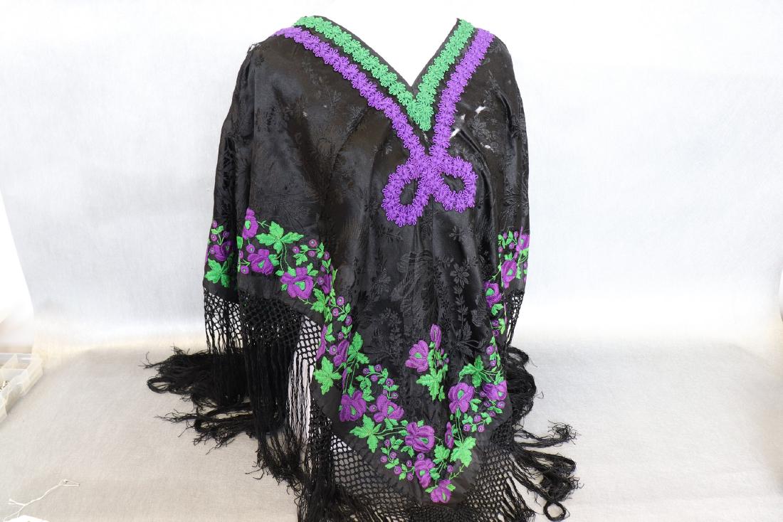 Vintage 1920's Black Silk Piano Shawl Poncho With: Vintage silk shawl-poncho features purple and green embroidery with 8" fringe. The embroidery and fringe is in great condition but the black silk has some small rips and damage.