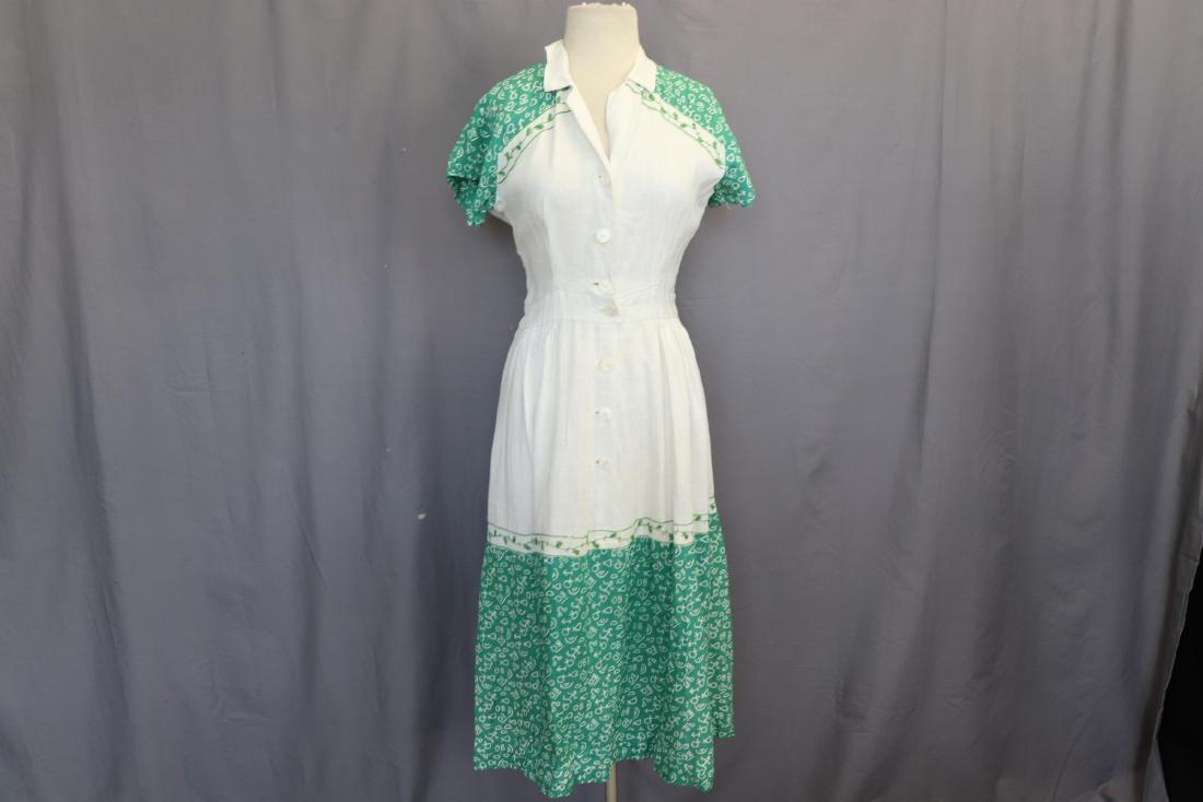 1950's Linen Dress With Green Accents: Pearl shell buttons at front, green embroidery and fabric accents. Measures 38" bust 30" waist, 46" long. The left sleeve has some damage, see photo.