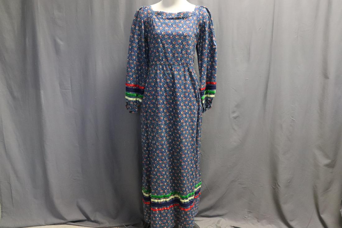 1970's Calico Print Maxi Dress: Square neckline, elastic at waist (needs to be replaced), decorative buttons on upper back and sleeves, 2 side pockets, ribbon trim detail. Measures approx. 36 bust, 32 waist, 55 long.