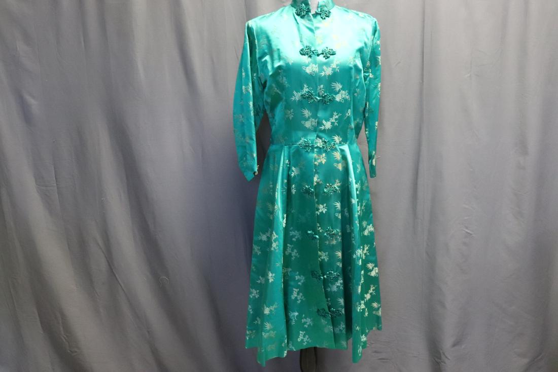 Vintage 1950's Green Brocade Cheongsam Robe: By Dynasty, side pockets, frog closures, slightly flared, measures approx. 38 chest, 30 waist, 44 long. Nice condition, no wear noted.