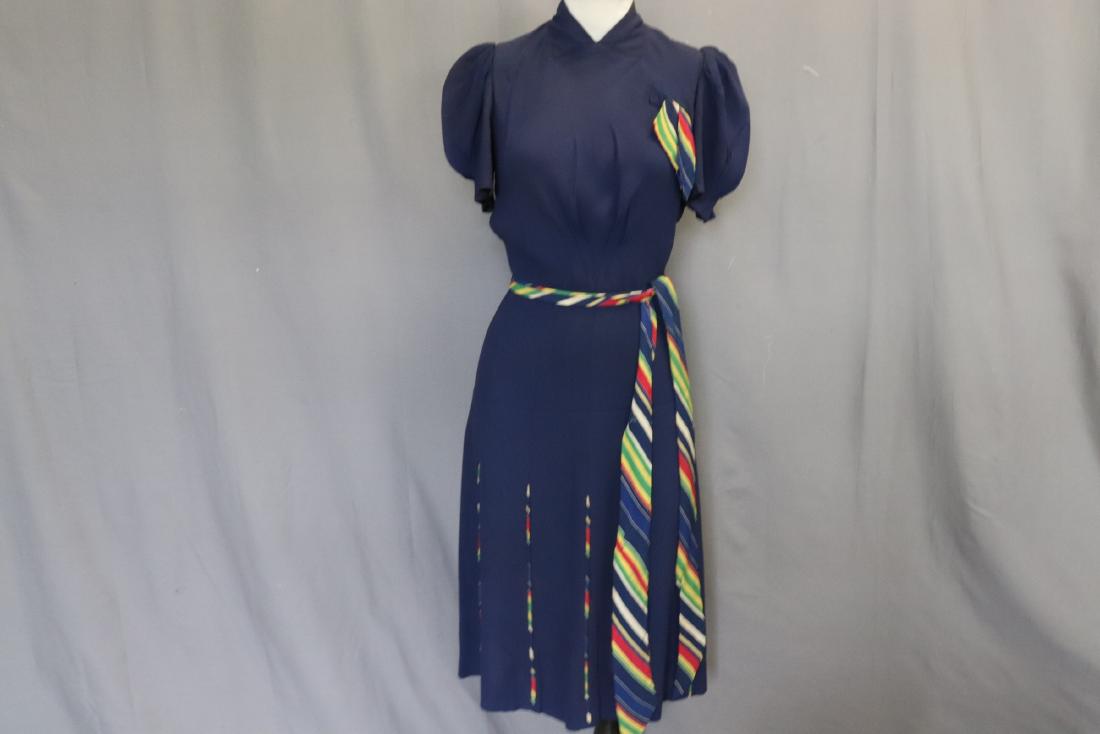 1940's Navy Blue Rayon Classic Dress: short pouf pleated sleeves, high V-neck, decorative tie at left breast faux pocket, sits at waist with striped fabric belt tie, paneled skirt with stiped insert, some under arm discoloration, see phot