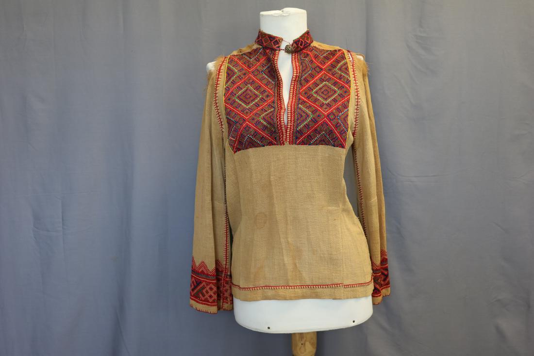 Early Persian Embroidered Ethnic Tunic: Appear to be silk embroidery, course cotton fabric, approx. 36 bust, 13 across shoulders. Unique top button. Rips on shoulders (from hangers?) and some broken threads in embroidery.