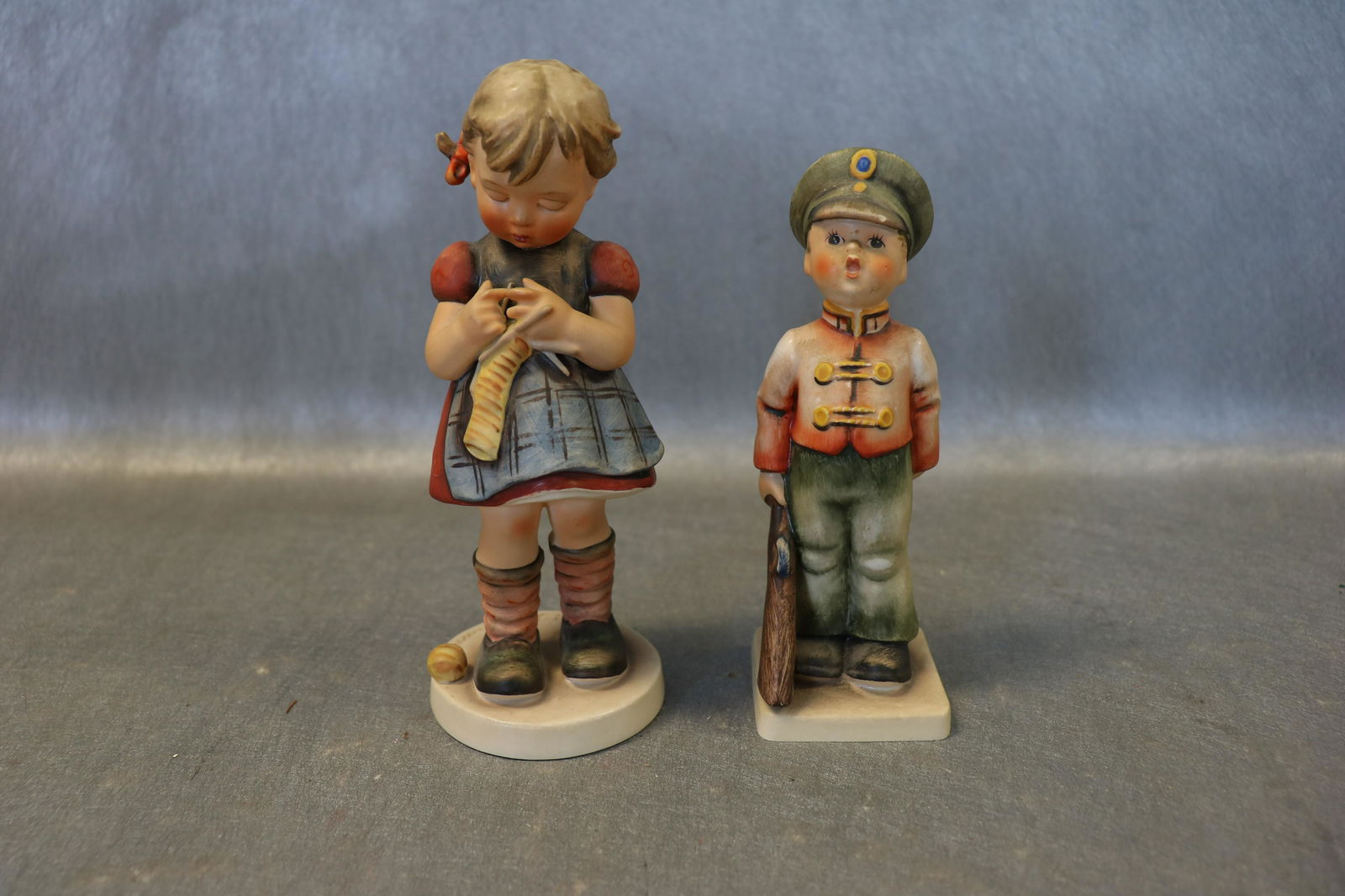2 Vintage Hummel Girl and Boy, Germany: Both marked W. Germany, W GOEBEL. Boy soldier marked 1957, 5 1/2" tall. Girl knitting is approx. 6 1/2' tall, marked 1963. Boy has flea bite on cap,