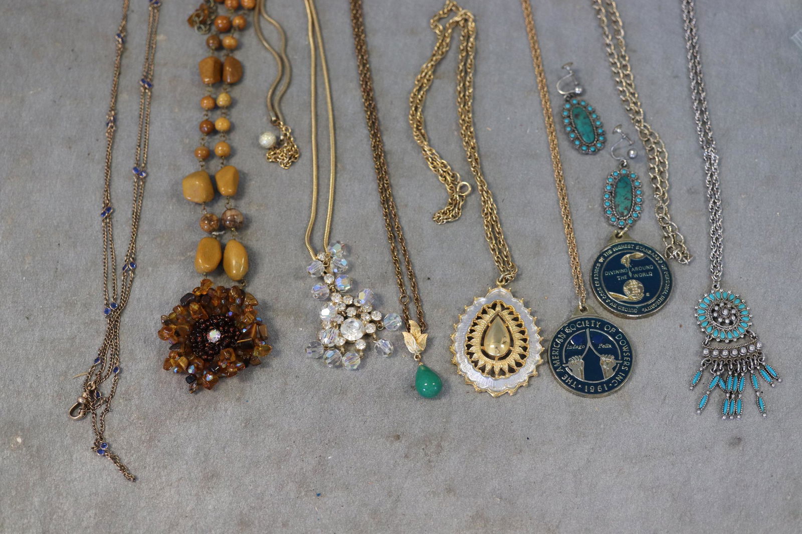 Bag Lot Costume Jewelry: Good costume jewelry lot includes necklaces, one pair screw-back earrings, 2 1961 Dowsers INC. awards.