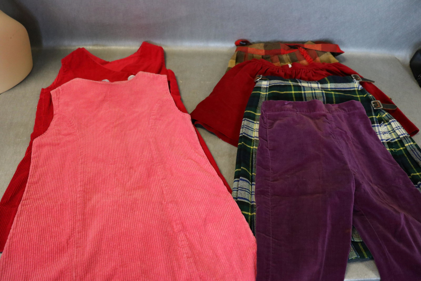 Lot of Vintage Girl's Clothing: 2-corduroy jumpers, Jordan Marsh wool plaid skirt from Scotland, plaid skirt with suspenders, purple velvet pants, red velvet skirt. All in good condition.