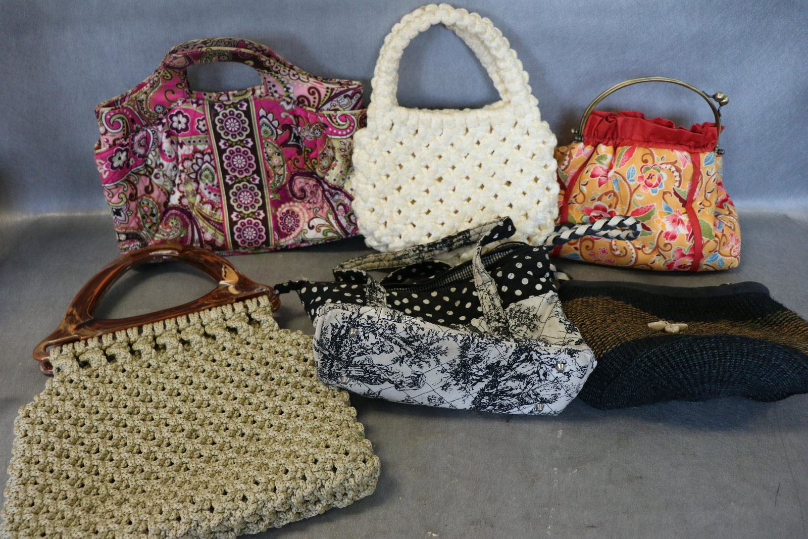 Lot of 6 Vintage Casual Handbags: Includes one Vera Bradley, lined with 4 inside pockets, light soil on the outside. 2-macrame bags (cream colored bag has light soil). 2 cotton fabric bags, one has light soil. Woven jute bag with shel