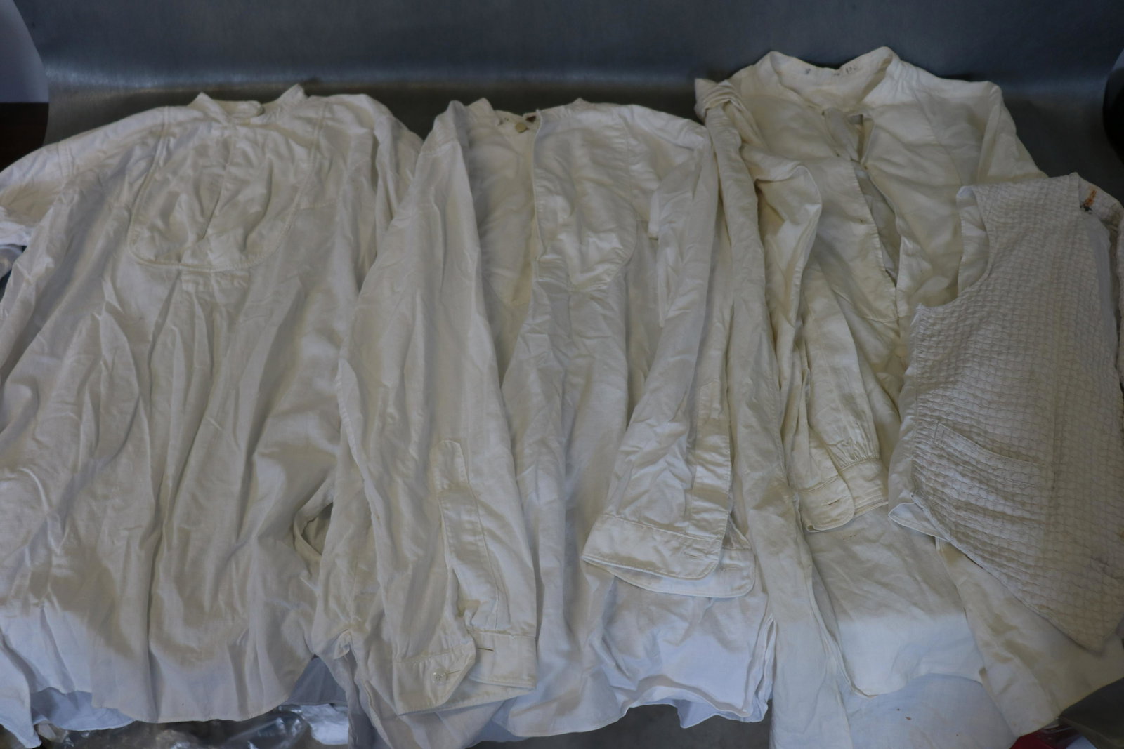 Lot Of 3 Antique Men's Dress Shirts, & Vest: 3-white muslin dress shirts, approx. 40" to 48" chest, very light scattered soil. Vest is 36" chest, 13" across shoulders, 20" long. Soil and small hole in upper back, armhole seam slight bit tattered