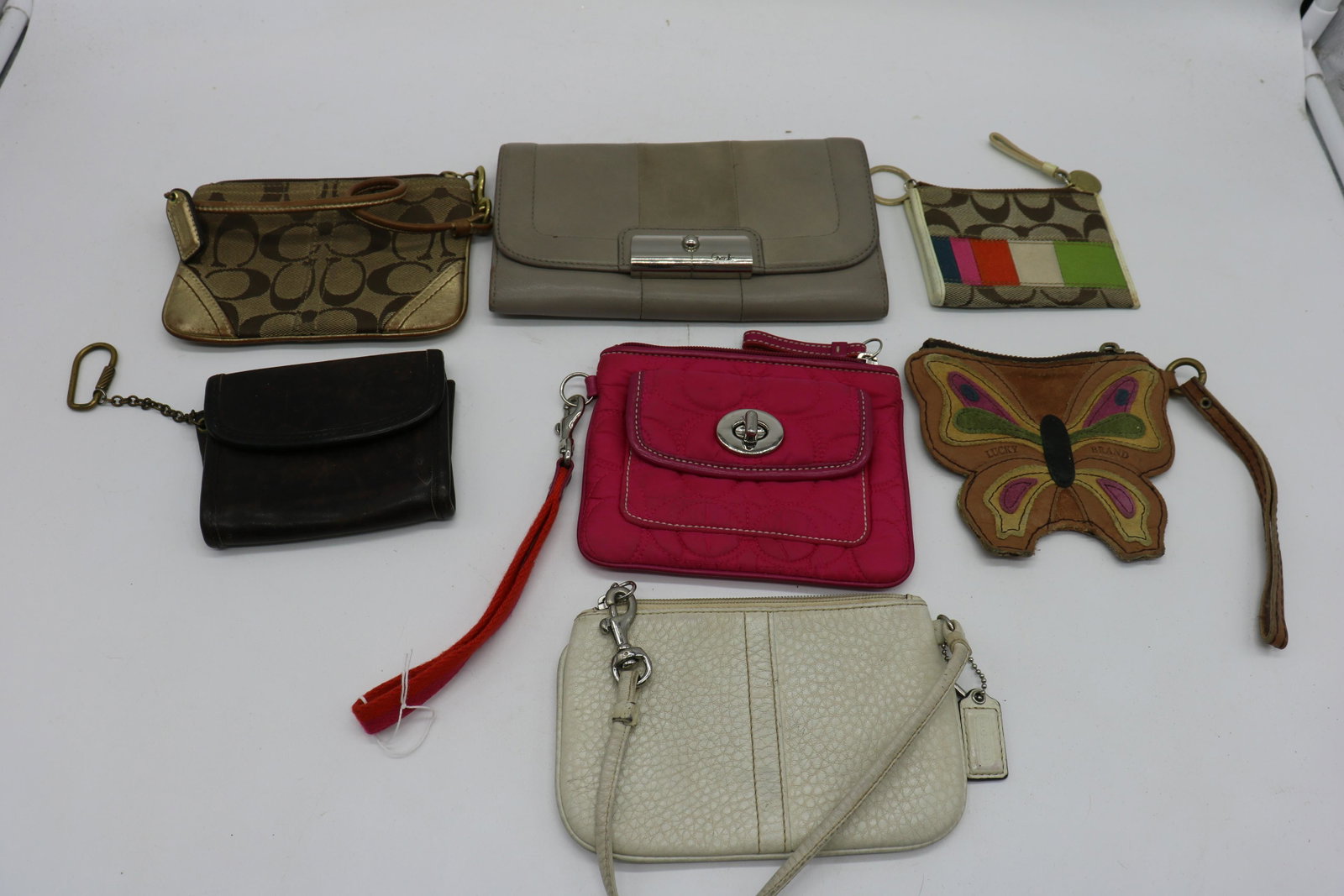 Lot of 6 Coach Wallets, Wristlets: Nice variety of wallets and wristlets, the light and medium brown wallets have a few light scratches, white leather wristlet and fabric mini purse/wallet have light soil. Lot also includes one Lucky B