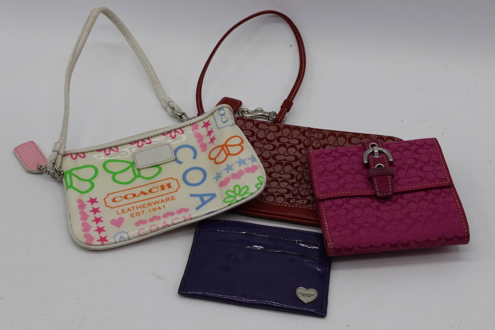 Lot Of 4 Vintage COACH Wallets, Billfold, Wristlets: Two wristlets approx. 4x6" (very light spot on the red one,. Pink cloth wallet approx. 4x4". Purple patent leather billfold/card holder 3x4".