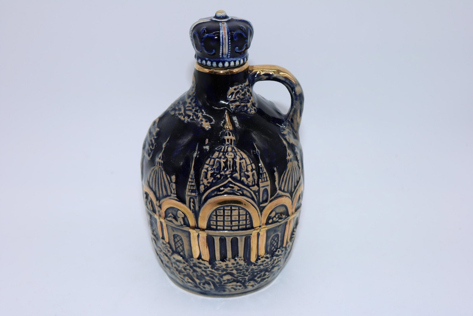 Vintage Musical Porcelain Decanter Jug: Cobalt blue with relief scene, liquor decanter with crown stopper, wind-up on bottom, Japan, approx. 6 1/2" tall, 5" wide.