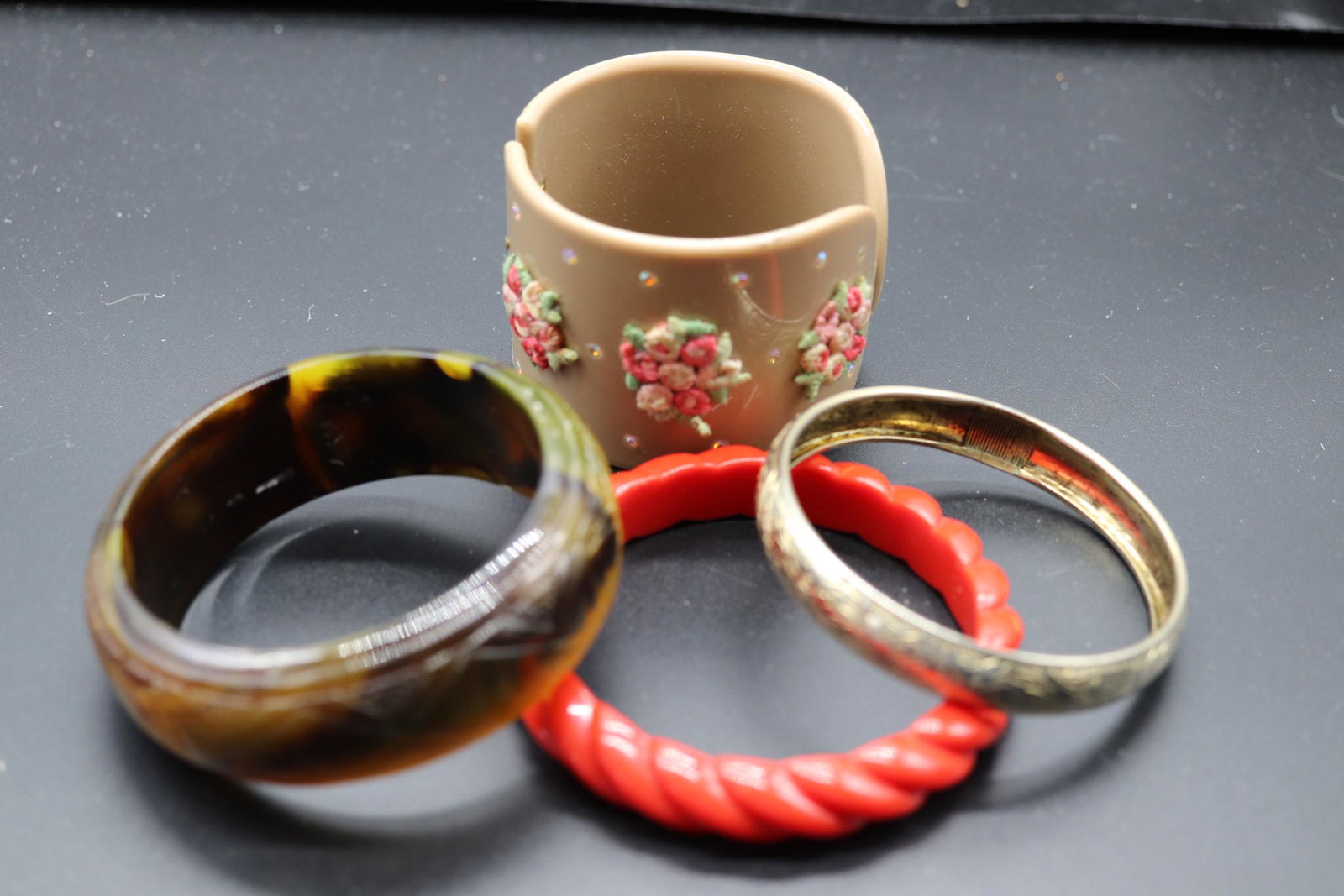 Lot of 4 Bangle Bracelets: etched no markings, plastic clamper with rhinestones and embroidered flowers, Red Plastic, carved greenish brown marblized, could be bakelite, lucite, not sure