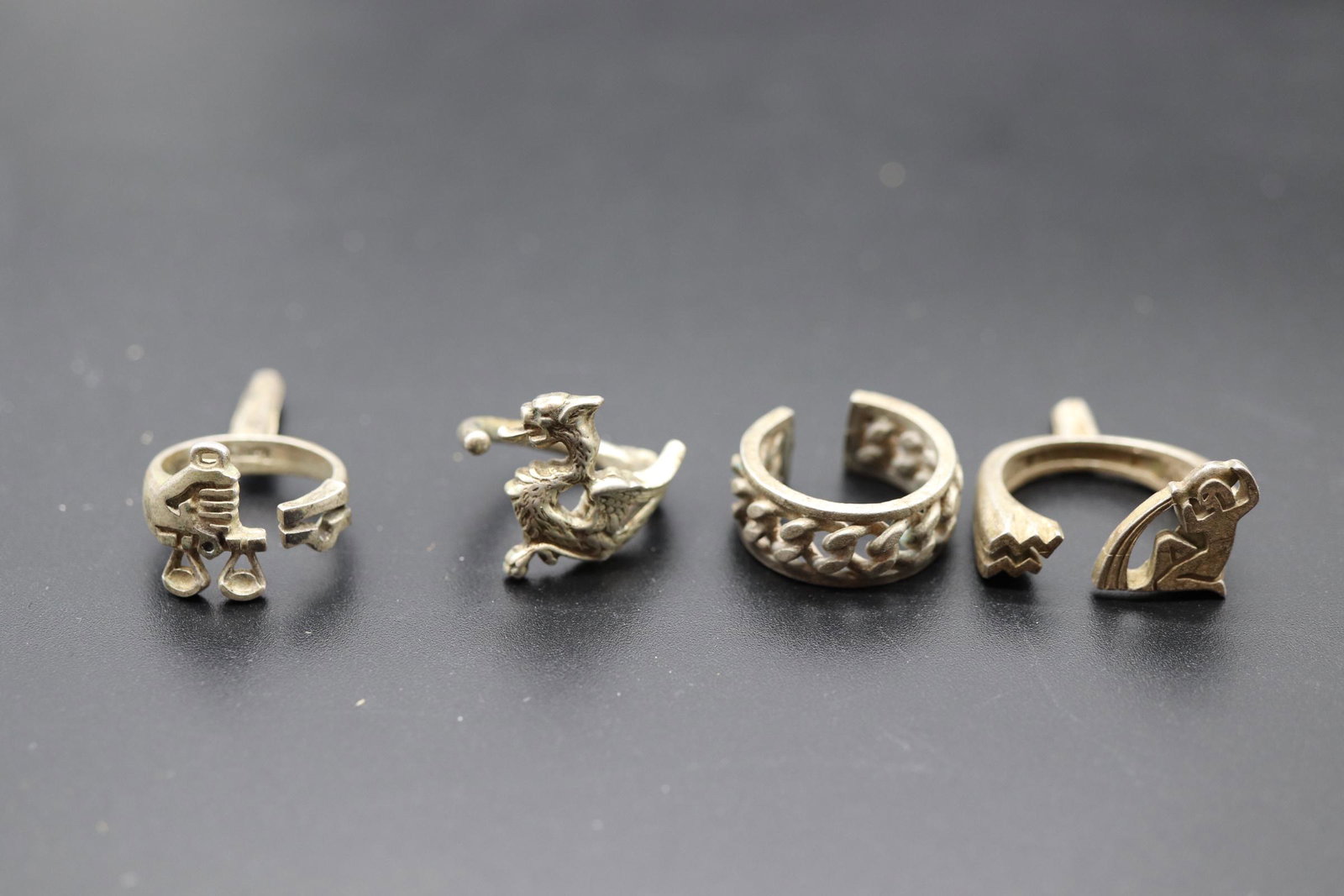 Lot of 4 Vintage Sterling Modernist Rings: marked sterling, 2 with posts tool/weapon, wing dragon size 6, braided chain style size 7, seated man with post size 10, scale with post size 7
