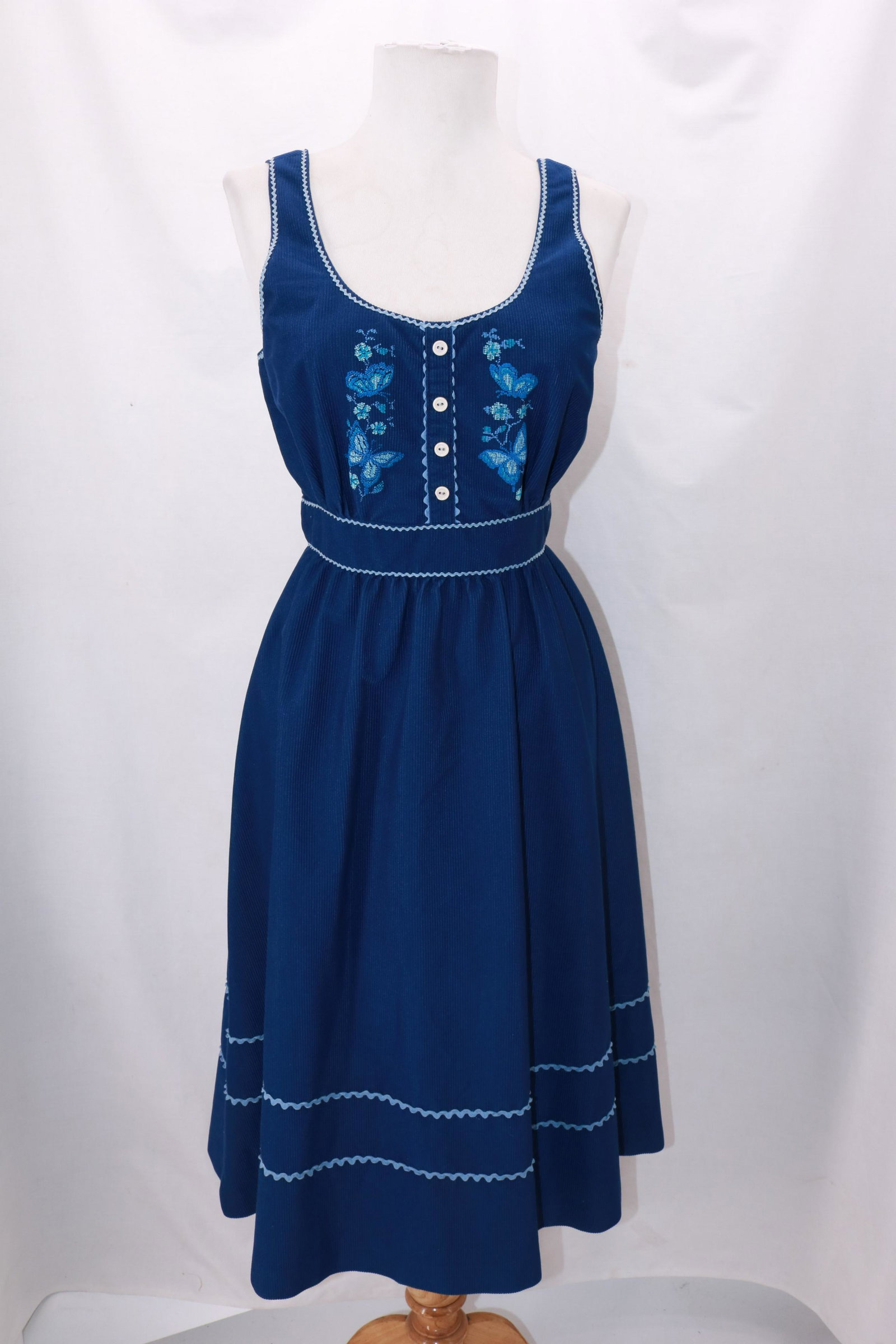 Vintage 1970's Navy Corduroy Jumper: Vintage 1970's Navy Corduroy Jumper with faux needlepoint decoration at the bodice with four buttons(not operating buttons- just for decoration). Light blue mini rick rack accents at the waist and top