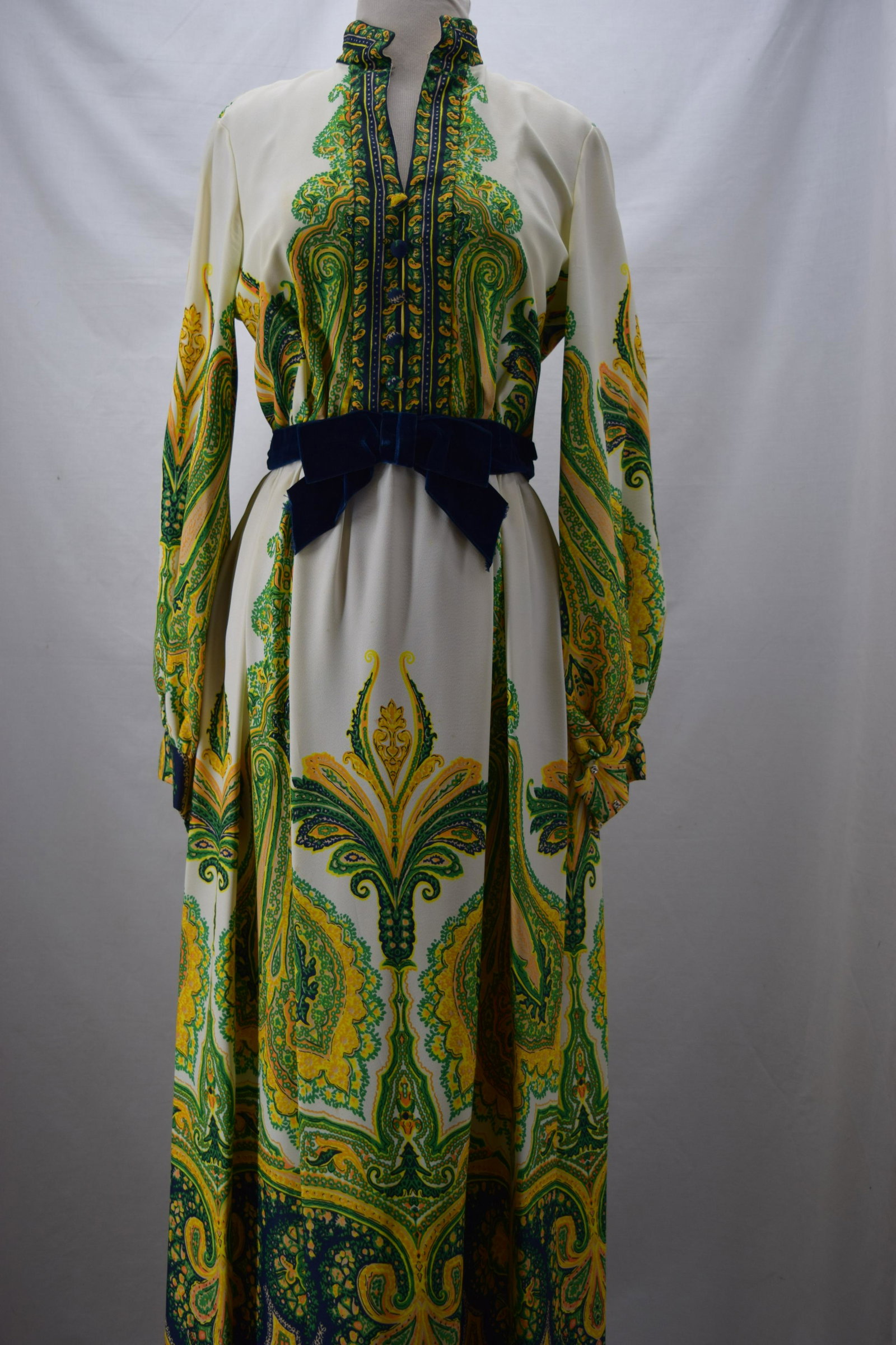 1960'S GALLERY DIVISION PAISLEY GOWN WITH VELVET BOW: BUST 36 WAIST 28, Polyester crepe. Gallery Division, Couleur International LTD printed fabric. Underarm stains and spotting on dress.