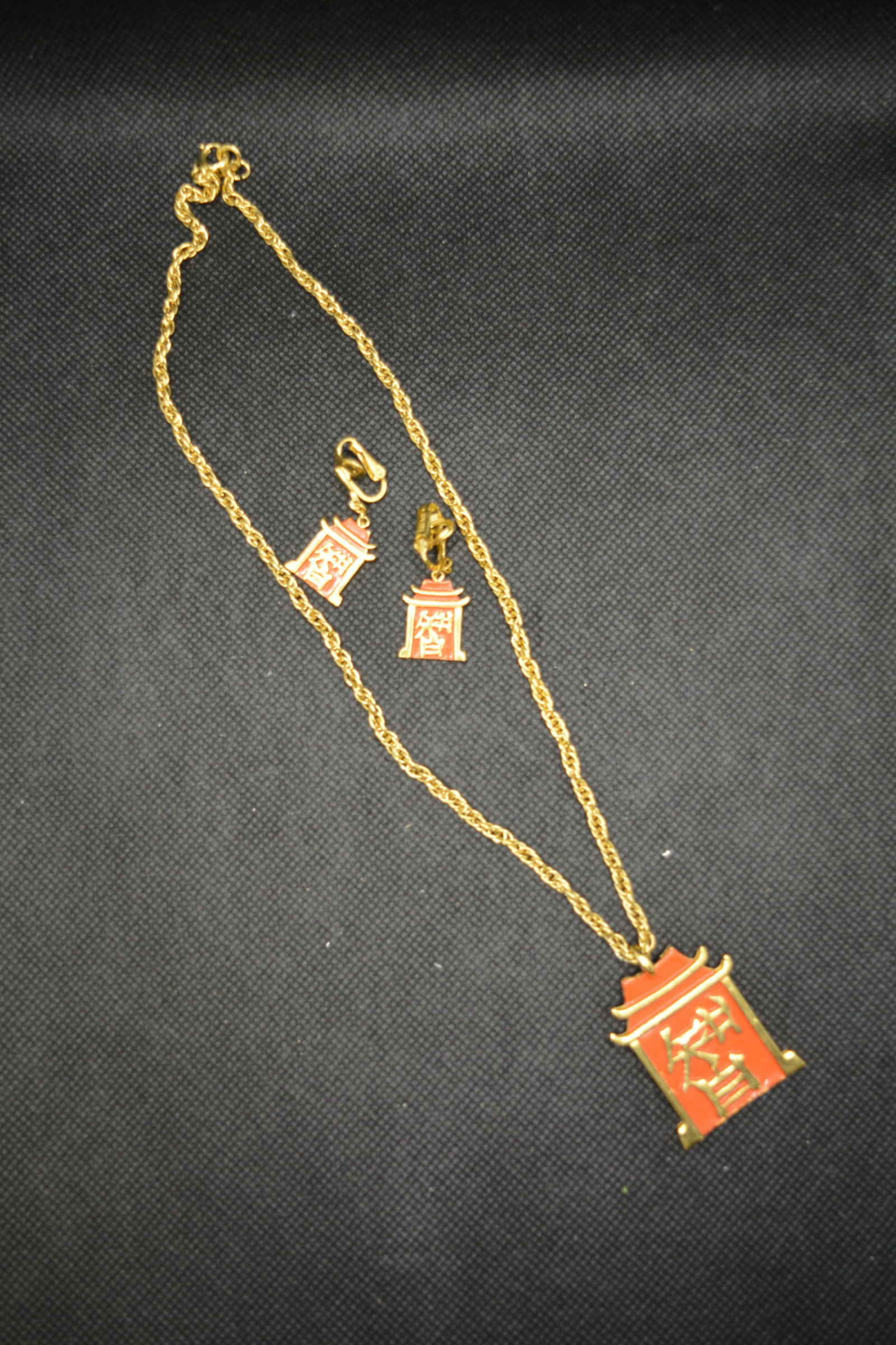 Vintage Trifari Asian Wisdom Necklace & Earring Set: clip on dangle earrings, gold tone with orange, chain approx. 18 inches, pendant approx. 1 1/2 inches