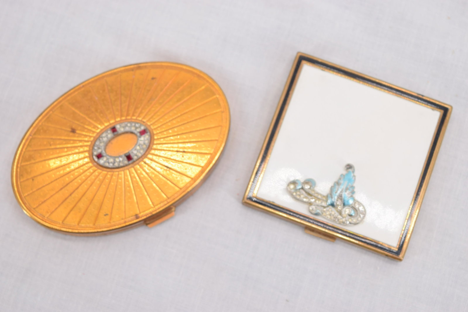 Vintage Powder Compacts with Rhinestone Decoration: Evans square compact with white enamel and rhinestones with blue leaf, the other Richard Hudnut oval withred stones and rhinestones