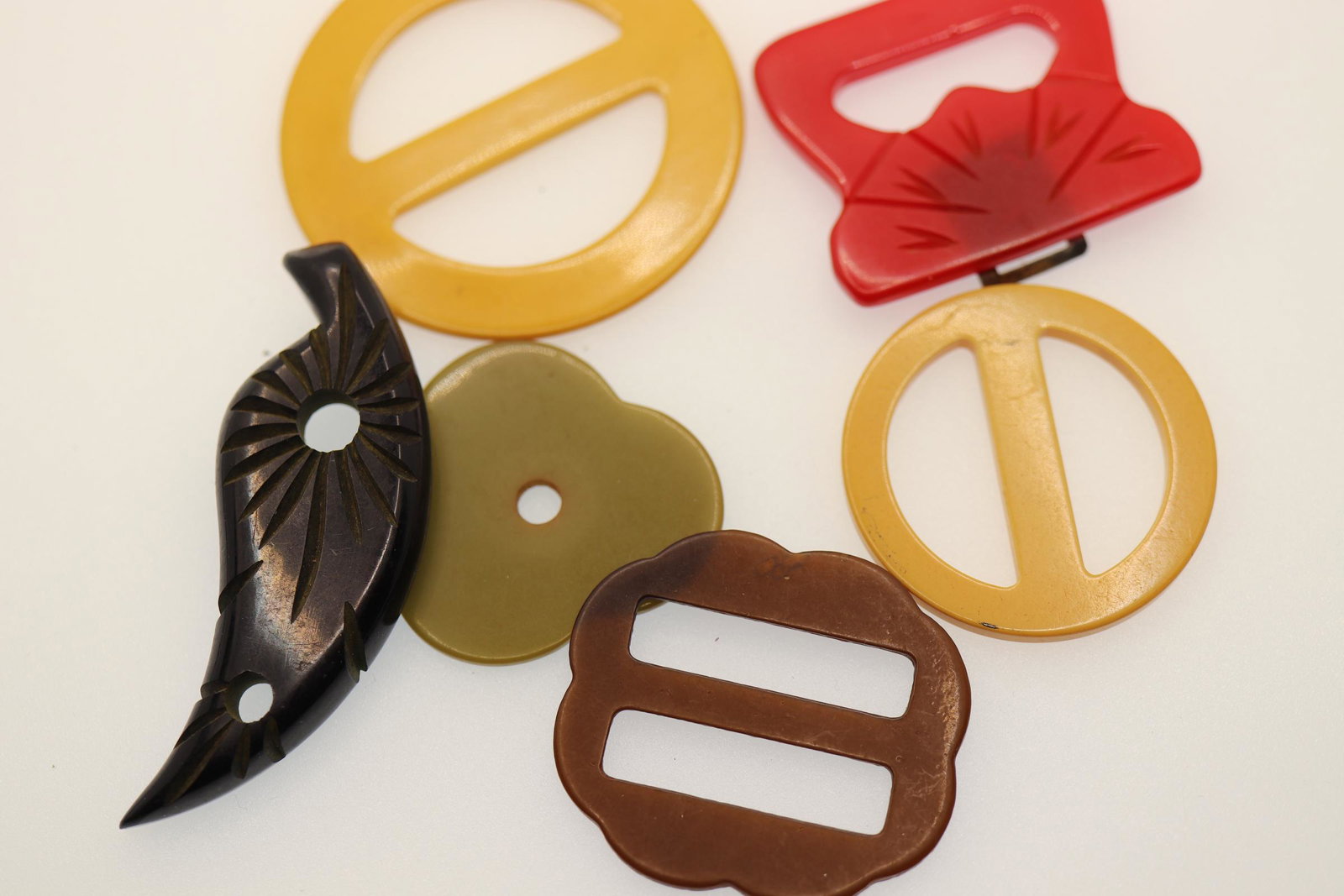 lot of 6 Bakelite 1940's Buckles: large 2 inch wide, 2 small buckles 1 1/2 wide, Black Feather dress/shoe clip 2 1/2, red half buckle 1 3/8, olive green (flat piece with single hole) 1 1/4 wide