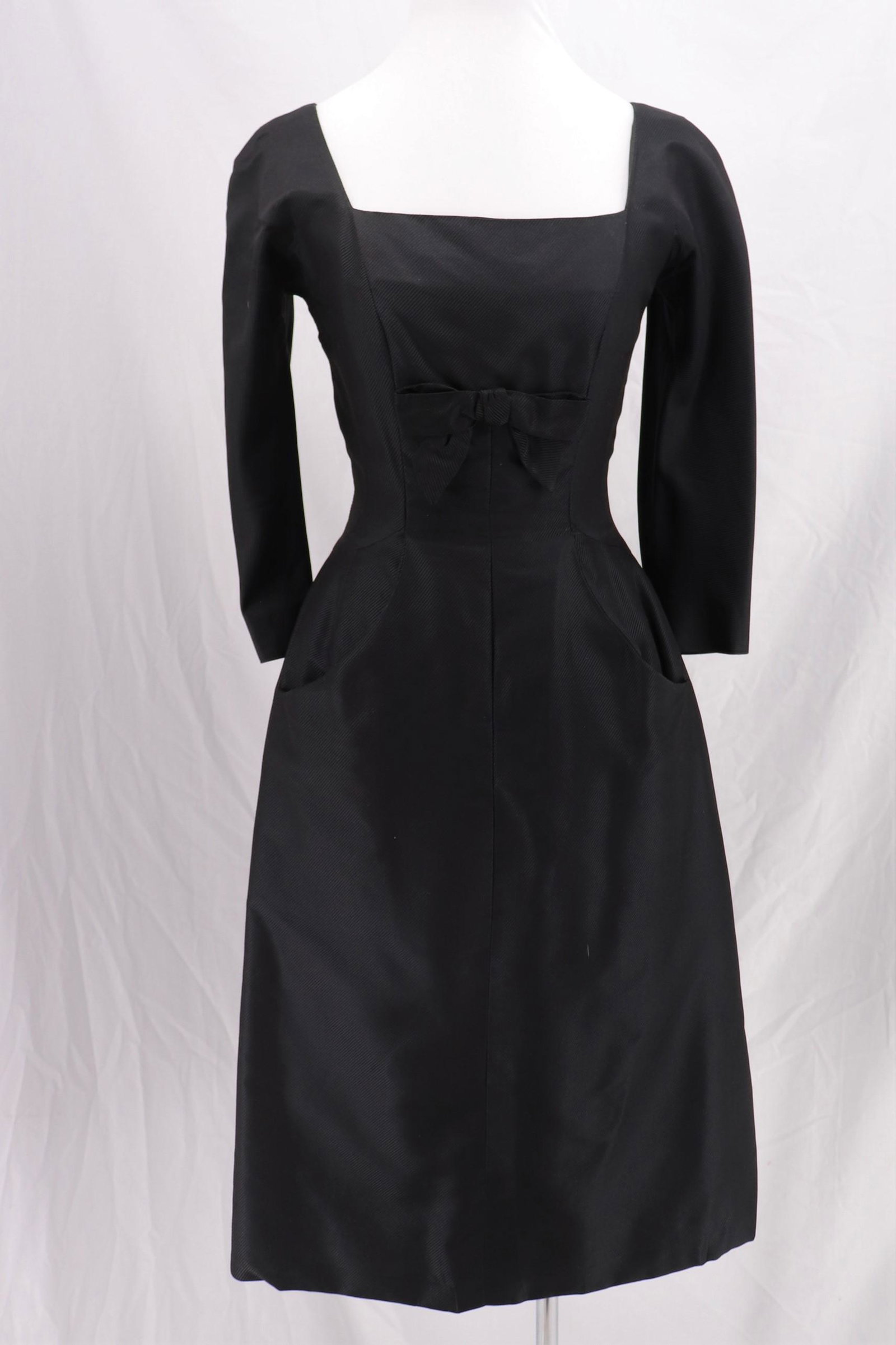 Vintage 1950's TALMARK NY Black Cocktail Dress: elbow length dolman sleeves, square neck, bow above waist, front scoop pockets, straight skirt, back metal zipper, darts at waist and hips, approx. 32 bust, 24 waist, good condition