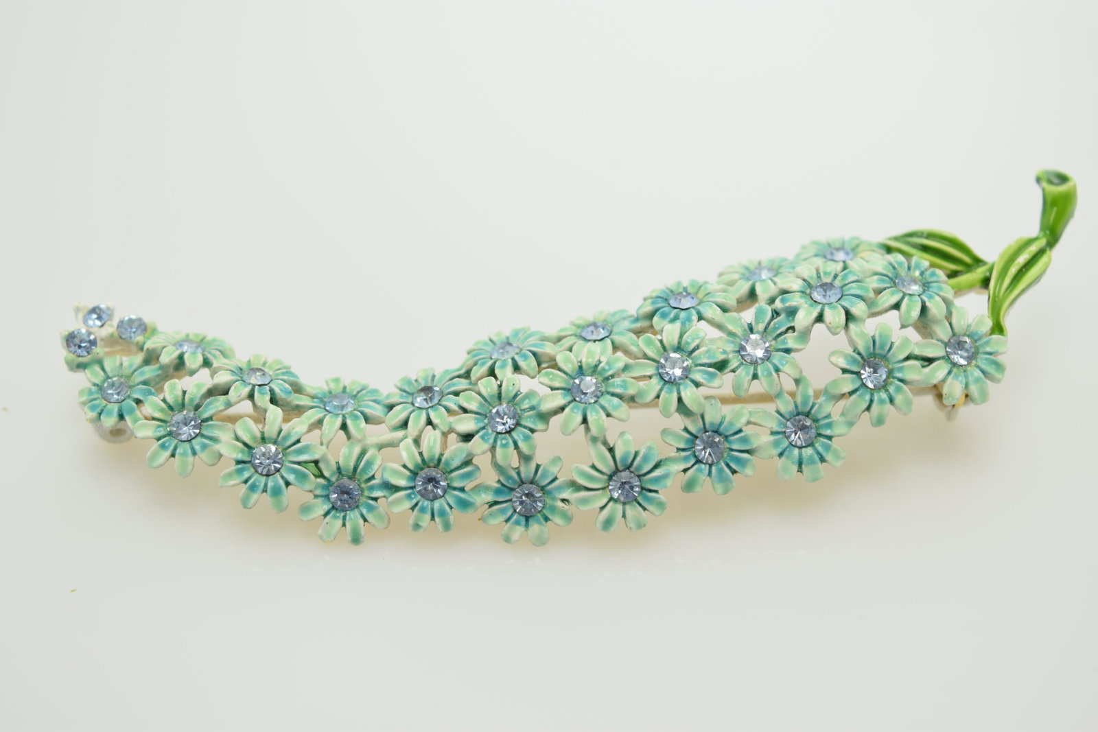A pin of blue enamel & blue rhinestones flowers.: A 3-1/4" long pin with shades of light blue enamel & rhinestones with green leaves. In good condition.