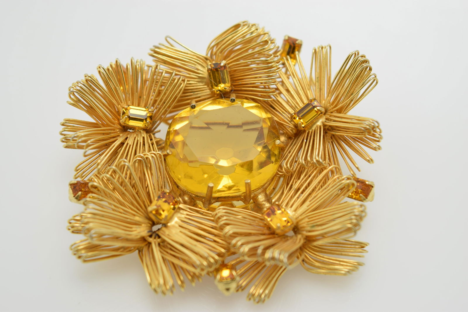 A large gold tone pin with a golden color center stone. (1 of 3)