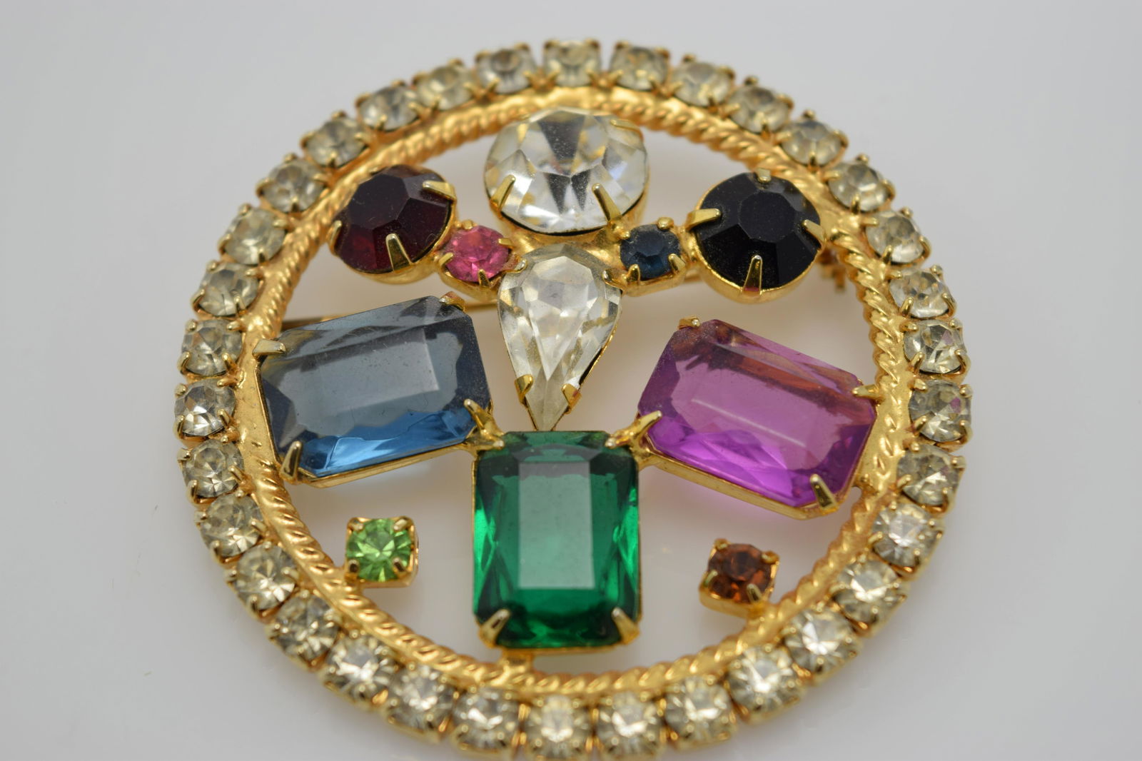 A vintage gold tone circle pin with clear and colorful (1 of 3)