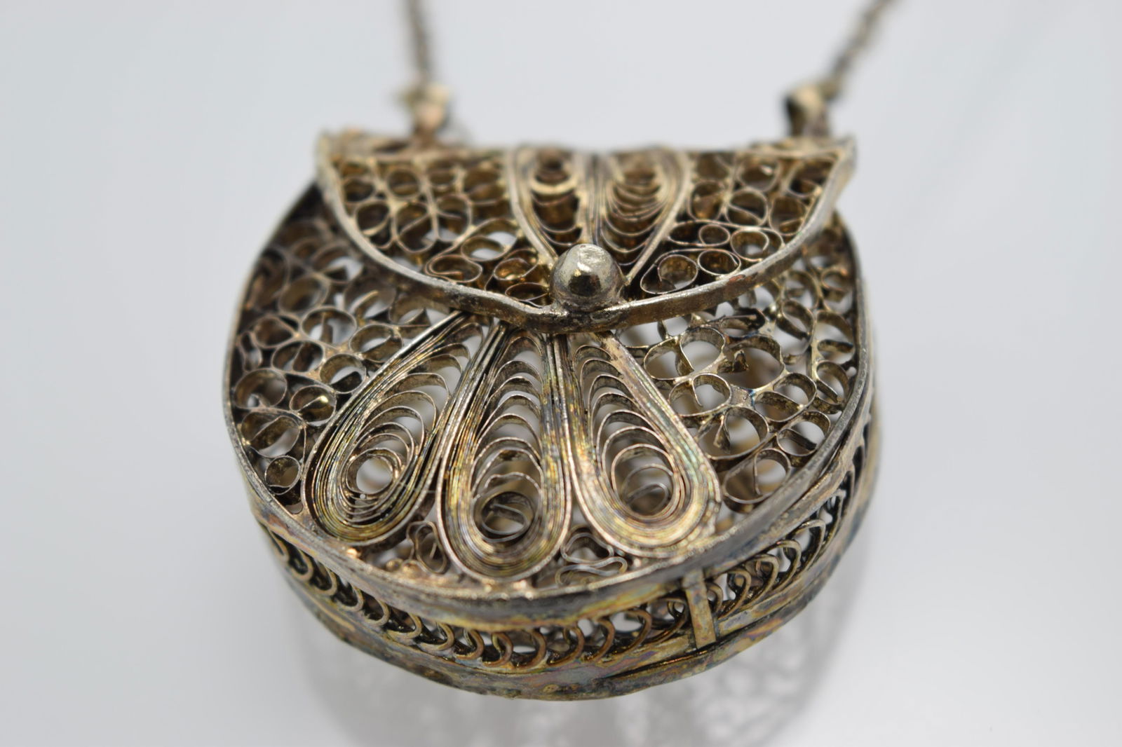 A silver tone necklace with a filigree purse pendant. (1 of 4)