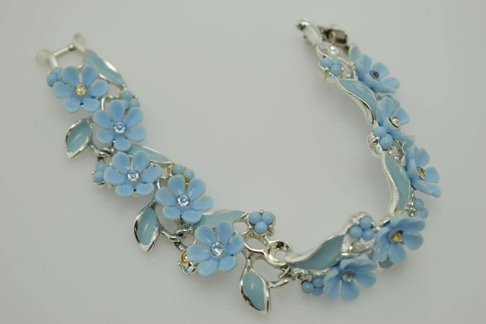A 1950's signed Coro light blue flower bracelet.: A 1950'2 signed Coro light blue plastic flower, approx. 7" silver tone bracelet with blue enamel and clear rhinestones. Many missing stones.