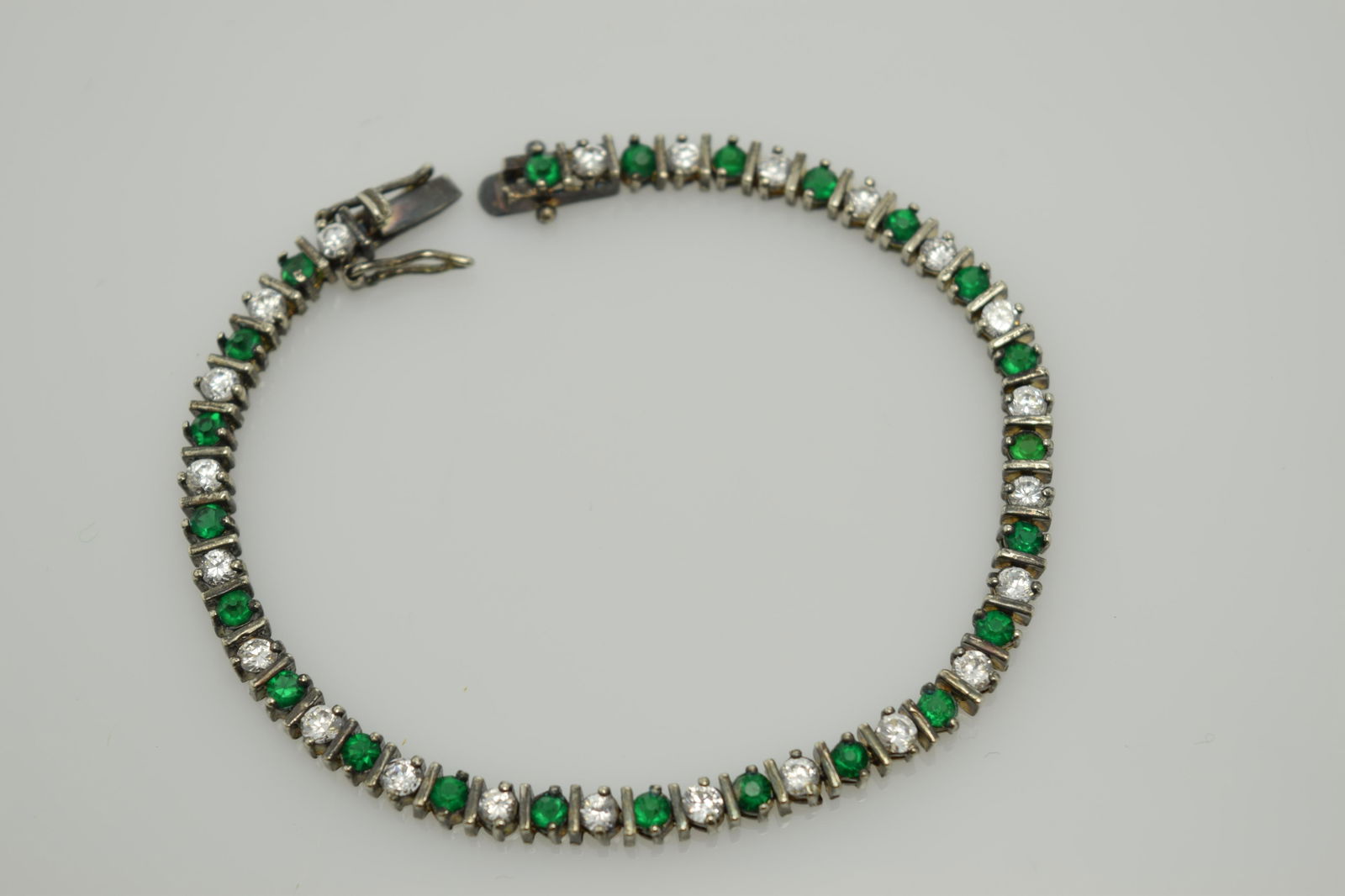 A sterling tennis bracelet made up of green and clear (1 of 2)
