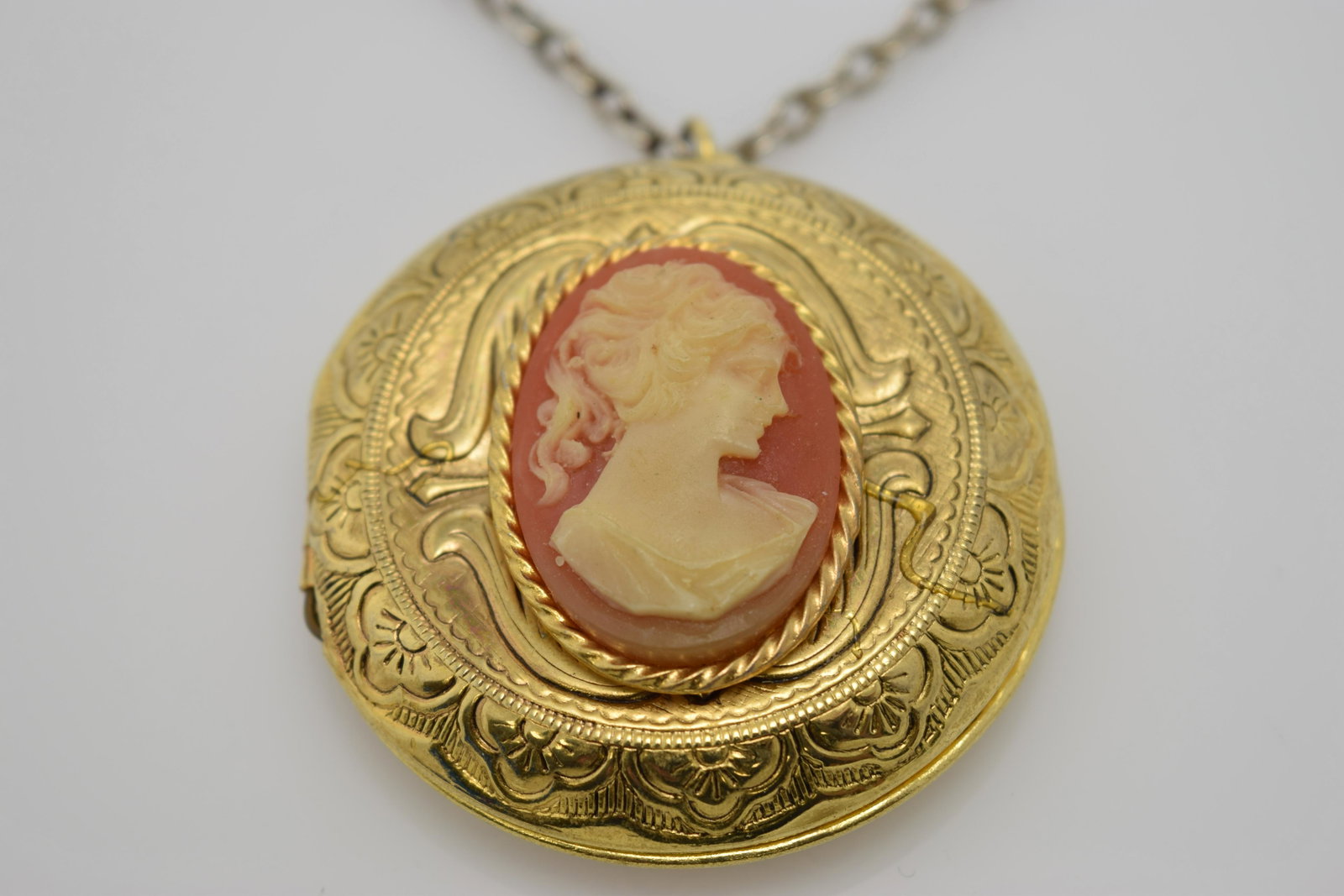 A chain necklace with a round locket with a faux cameo.: An approx. 24" chain necklace with a 1-1/2" diameter gold tone locket with a faux cameo. The locket does not close well & the gold tone is worn off of the chain.
